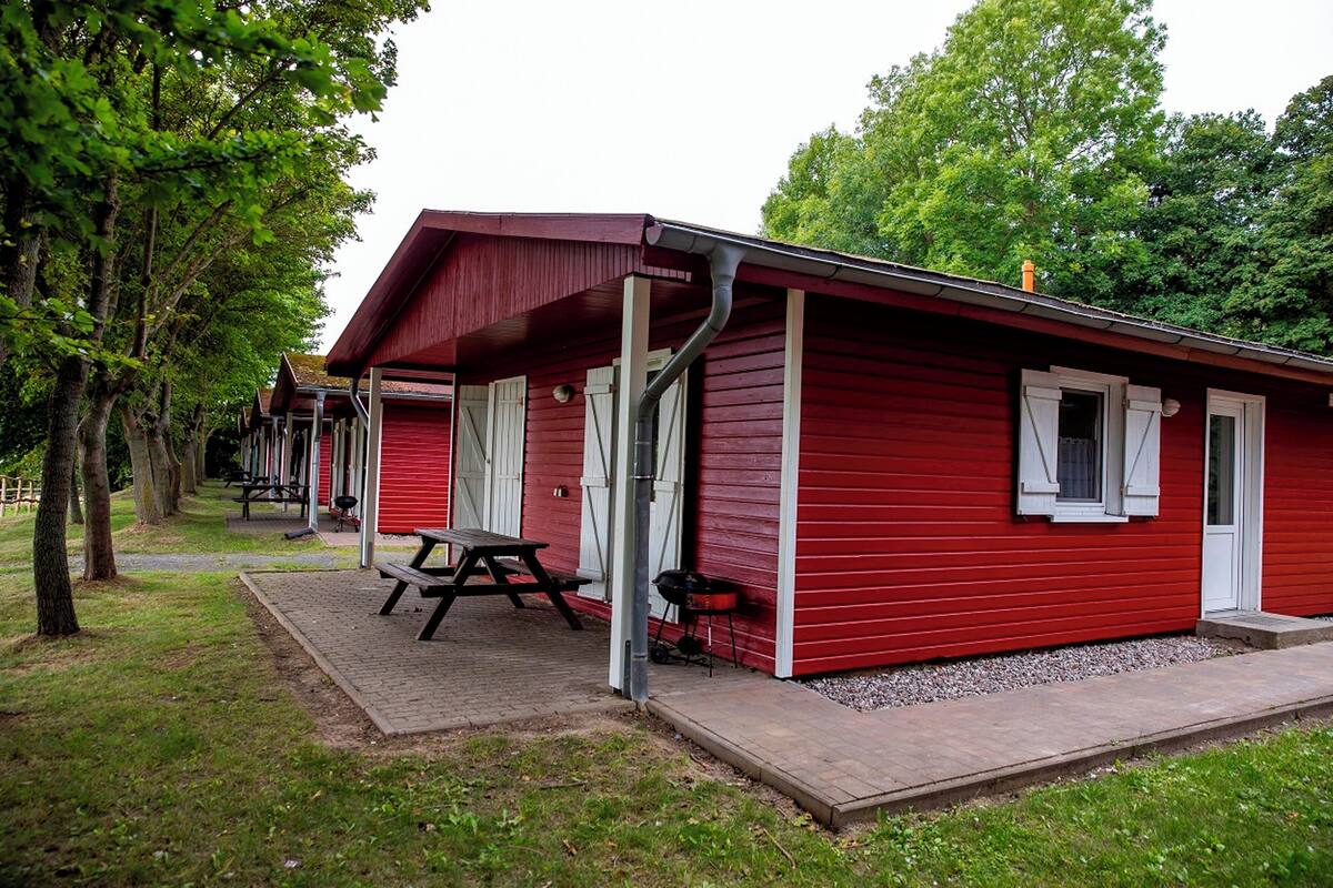 A red cabin with a picnic table and grill outside.