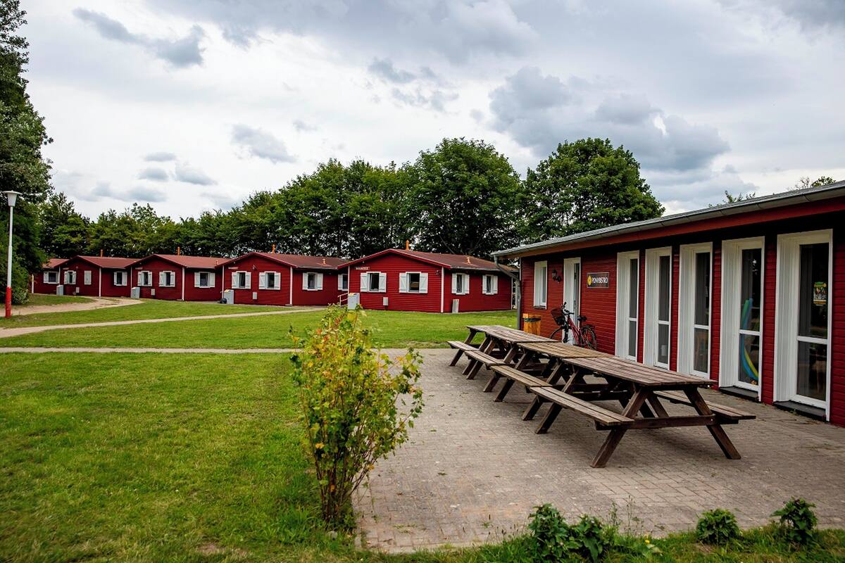 A row of red cabins with white trim, a picnic table, and a bicycle in the foreground.