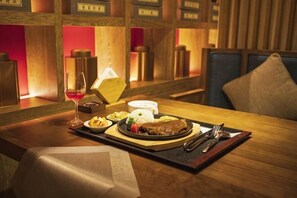 Une table à manger avec une assiette de nourriture, un verre de vin rouge et une bougie.
