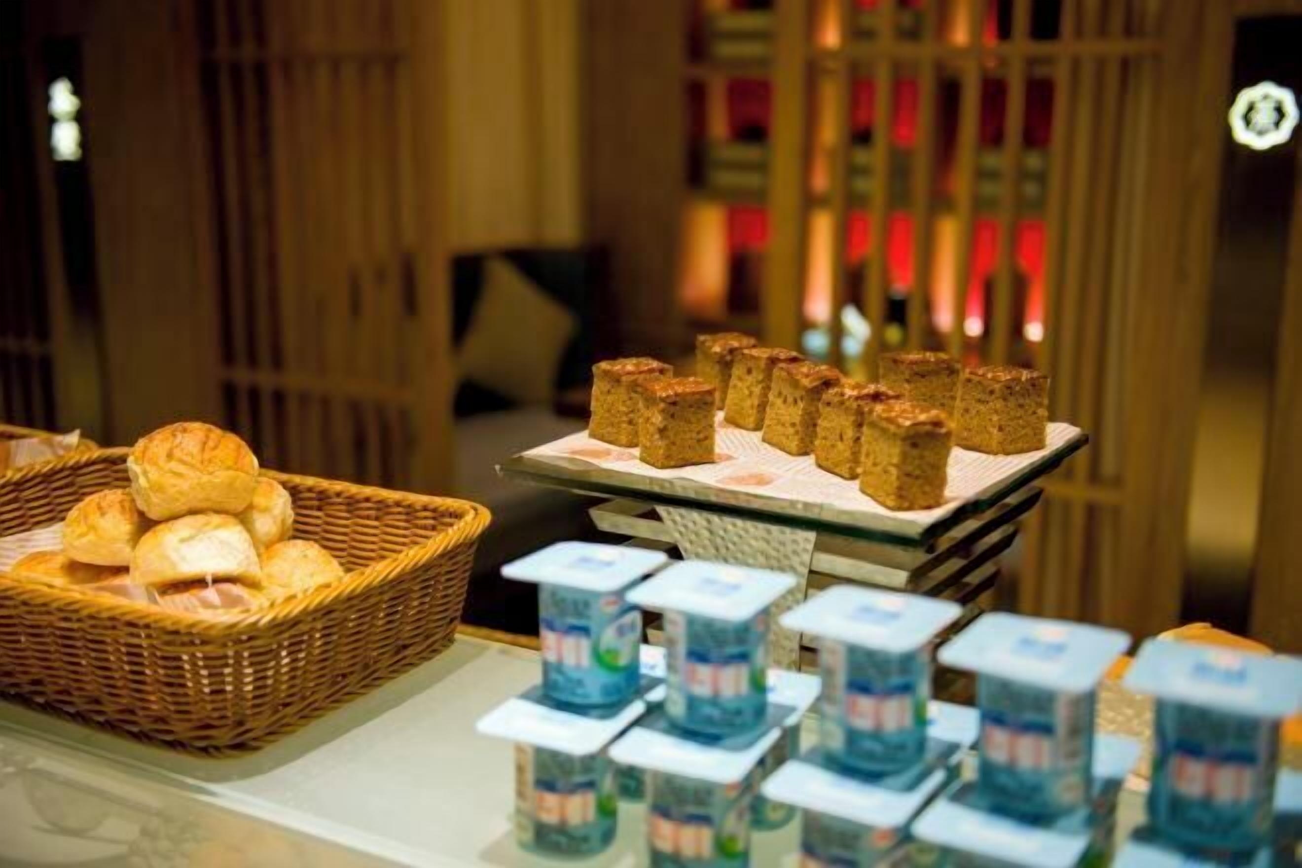 A buffet with bread rolls and packaged food items.