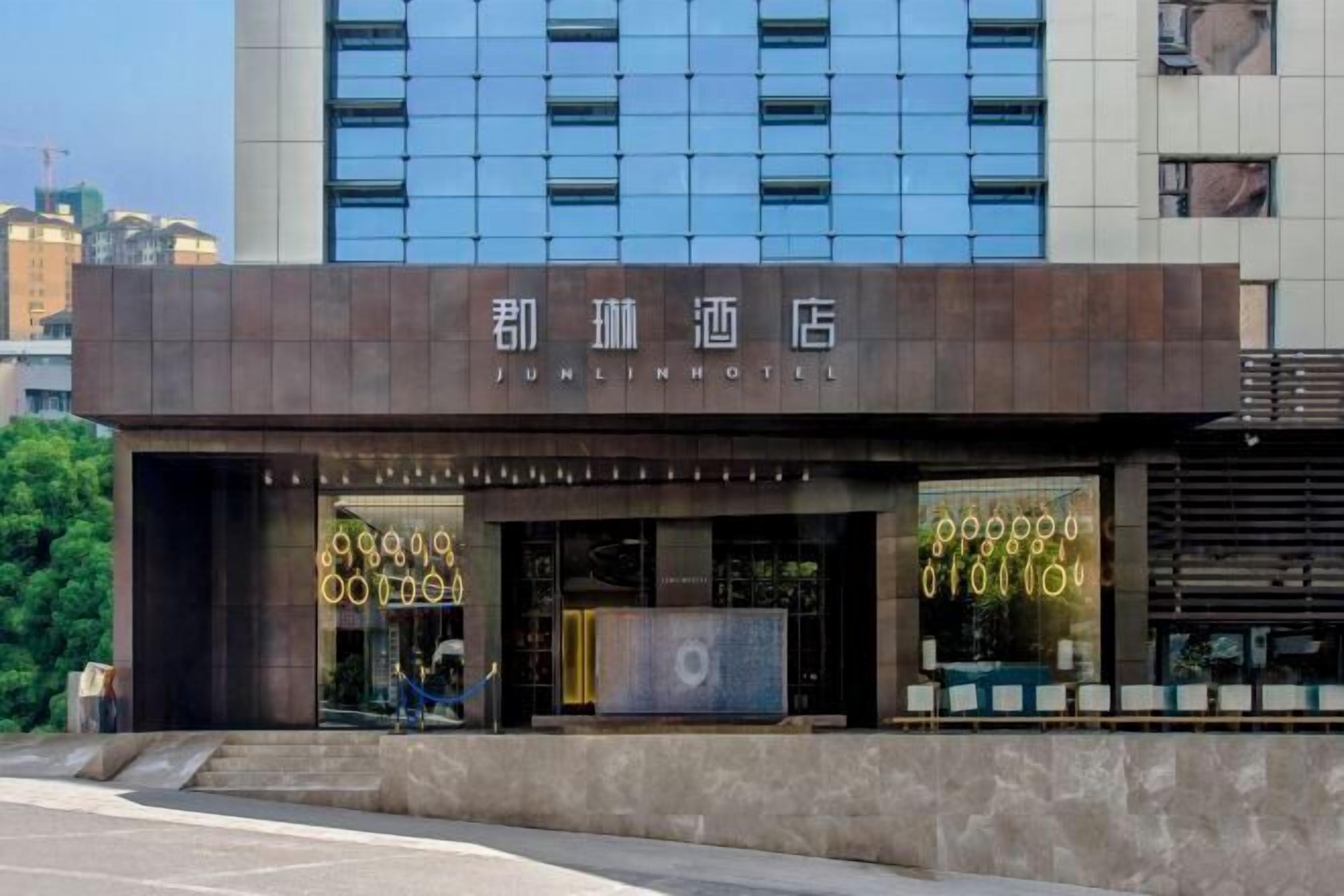 A Junlin Hotel with a modern facade, large windows, and a visible entrance.
