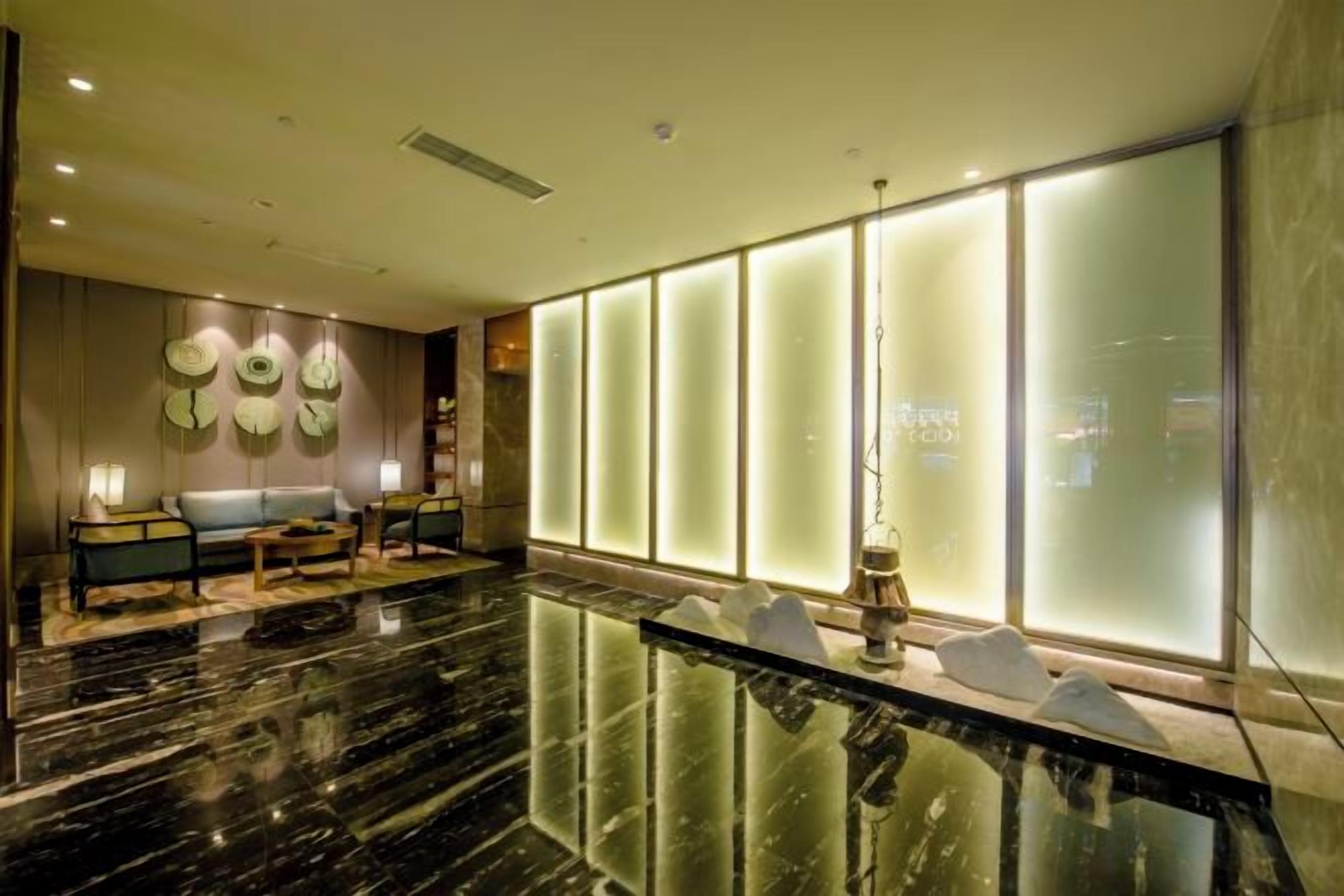Een moderne lobby met een marmeren vloer, een zithoek en grote glaspanelen met een frosted afwerking.