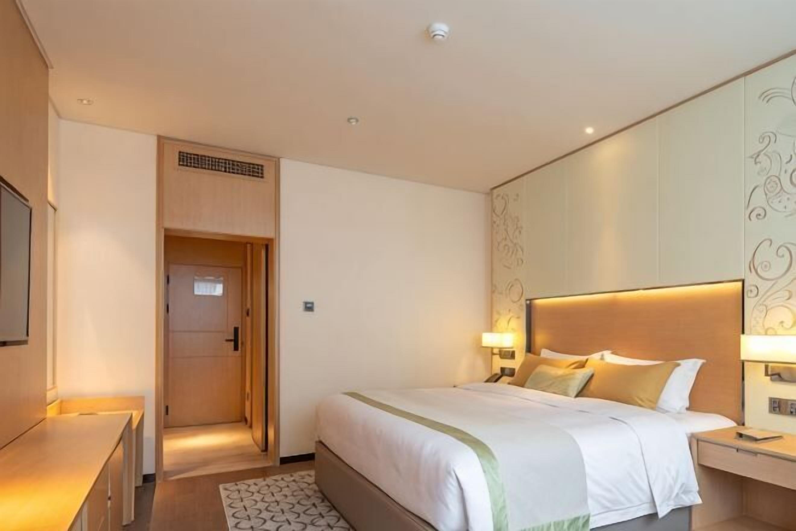 Une chambre d’hôtel comprenant un lit, des tables de chevet, une télévision et une porte donnant sur une autre pièce.