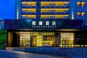 Un hotel con fachada moderna, señalización iluminada y una entrada bien iluminada.