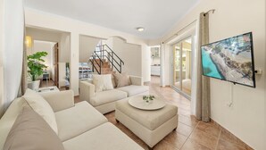 Ein großzügiger Wohnbereich mit einer Sofagarnitur, einem Couchtisch, einem Flachbildfernseher und einer Treppe, die zu einer oberen Etage führt.