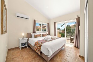 Une chambre d’hôtel comprenant un lit, une table de chevet, un appareil de climatisation, une fenêtre avec des rideaux et une vue sur l’extérieur.