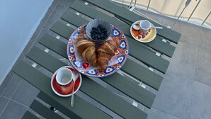 Ein Balkon mit einem Frühstückstisch, komplett mit Croissants, einer Schale Blaubeeren und einer Kaffeetasse.