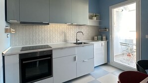 Eine moderne Küche mit weißen Schränken, einem schwarzen Backofen und einer gefliesten Spritzschutzwand.