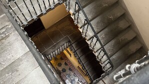 A staircase with a metal railing and a patterned floor.
