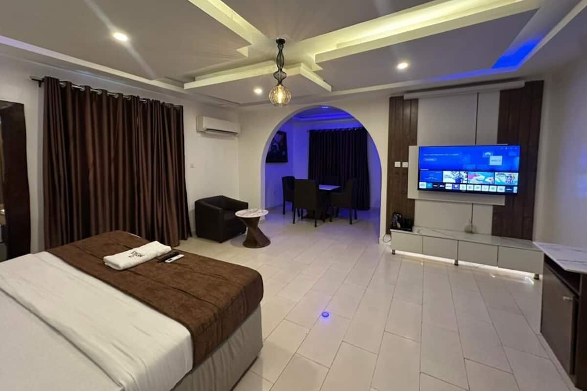 A hotel room with a bed, a TV, a desk, and a seating area.