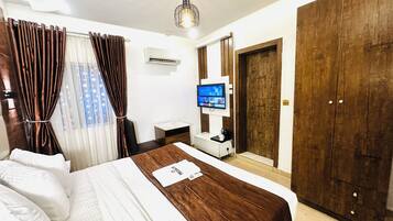 A hotel room with a bed, a desk, a TV, and a wardrobe.