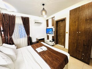 A hotel room with a bed, a desk, a TV, and a wardrobe. - Presken Waters (Lagos)