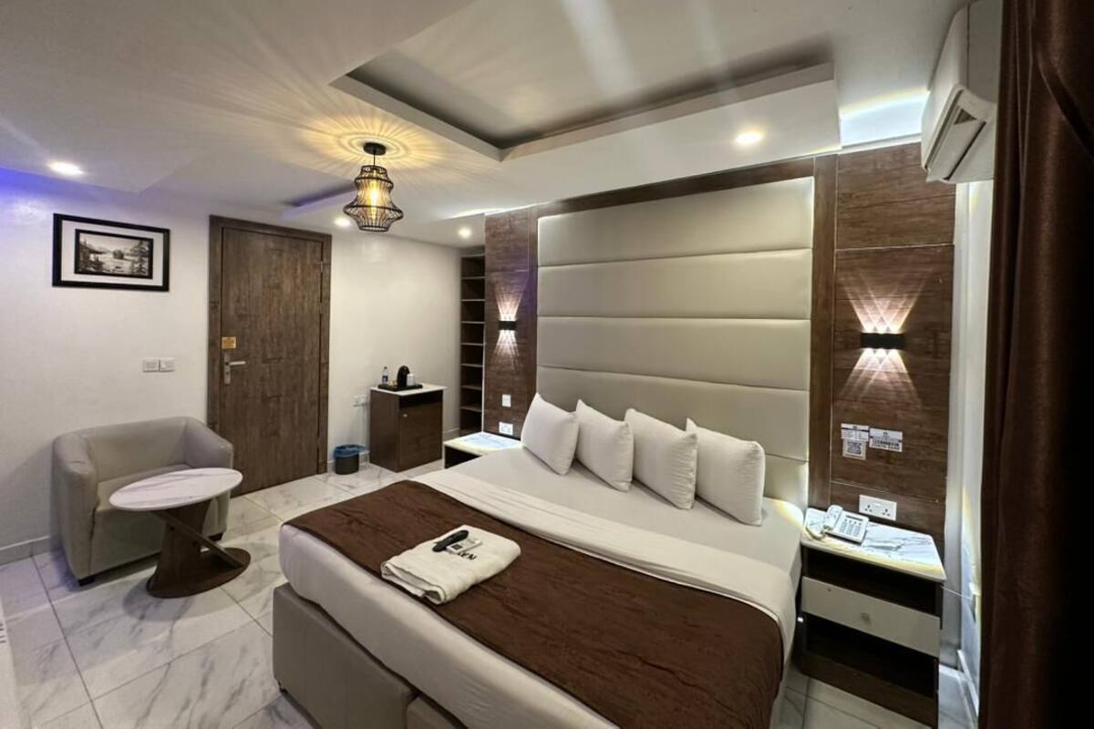 A modern bedroom with a large bed, bedside tables, a chair, and a desk.