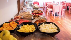 Un buffet proposant une variété de fruits, de viennoiseries et de pains.