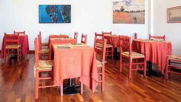Un comedor con varias mesas y sillas, cada una cubierta con un mantel rojo.