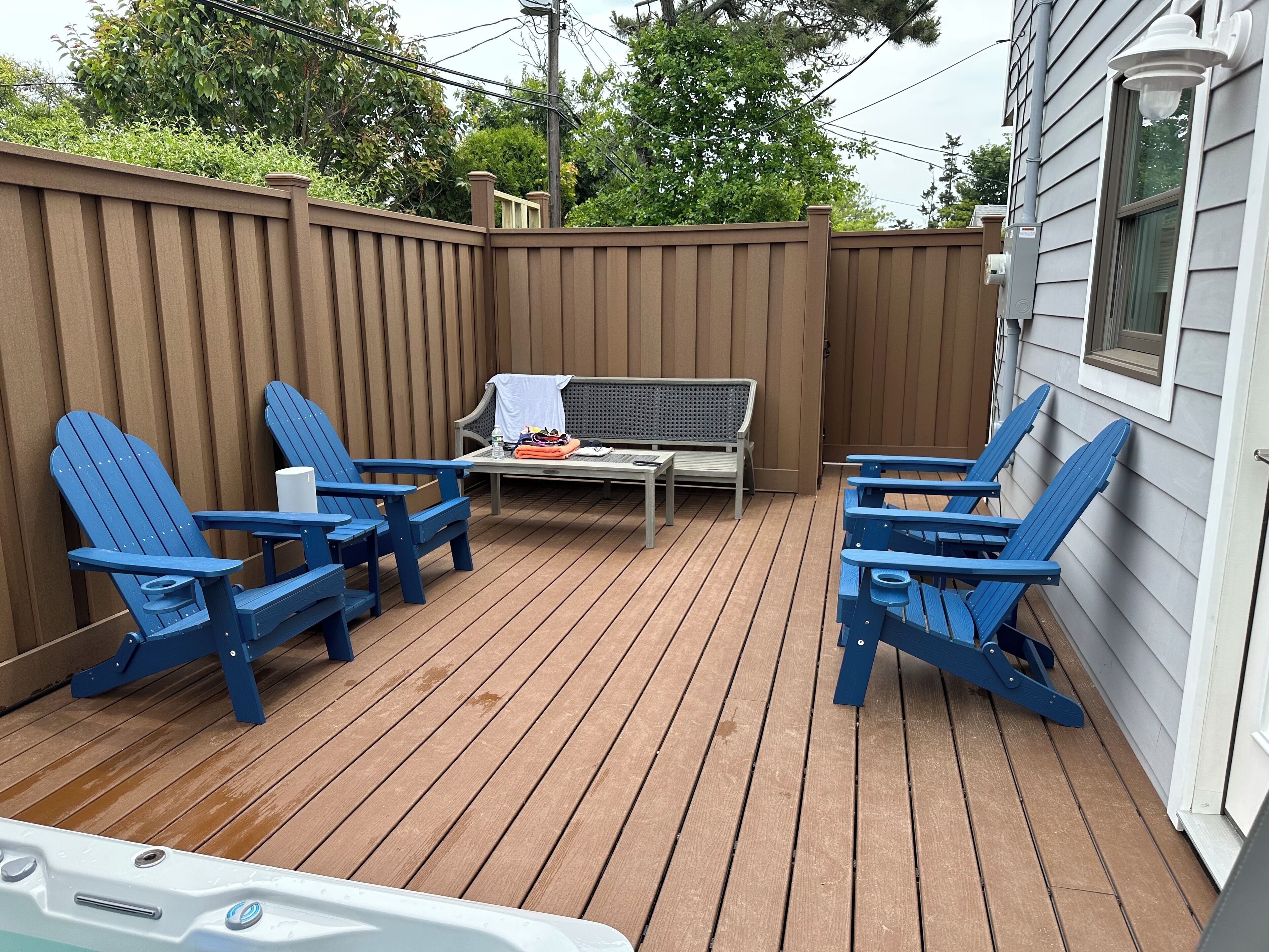 A deck with blue Adirondack chairs, a small table, and a bench.