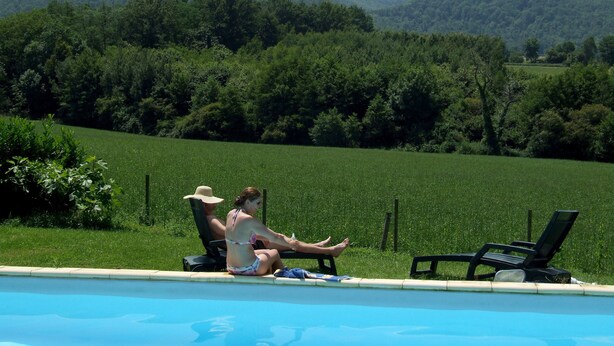Un espace aménagé au bord de la piscine, offrant une vue sur des collines verdoyantes et des montagnes.