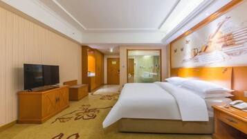 A hotel room with a large bed, a television, a wooden cabinet, and a carpet with a floral pattern.