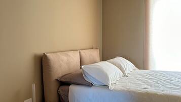A modern bedroom with a bed, a nightstand, and a window.