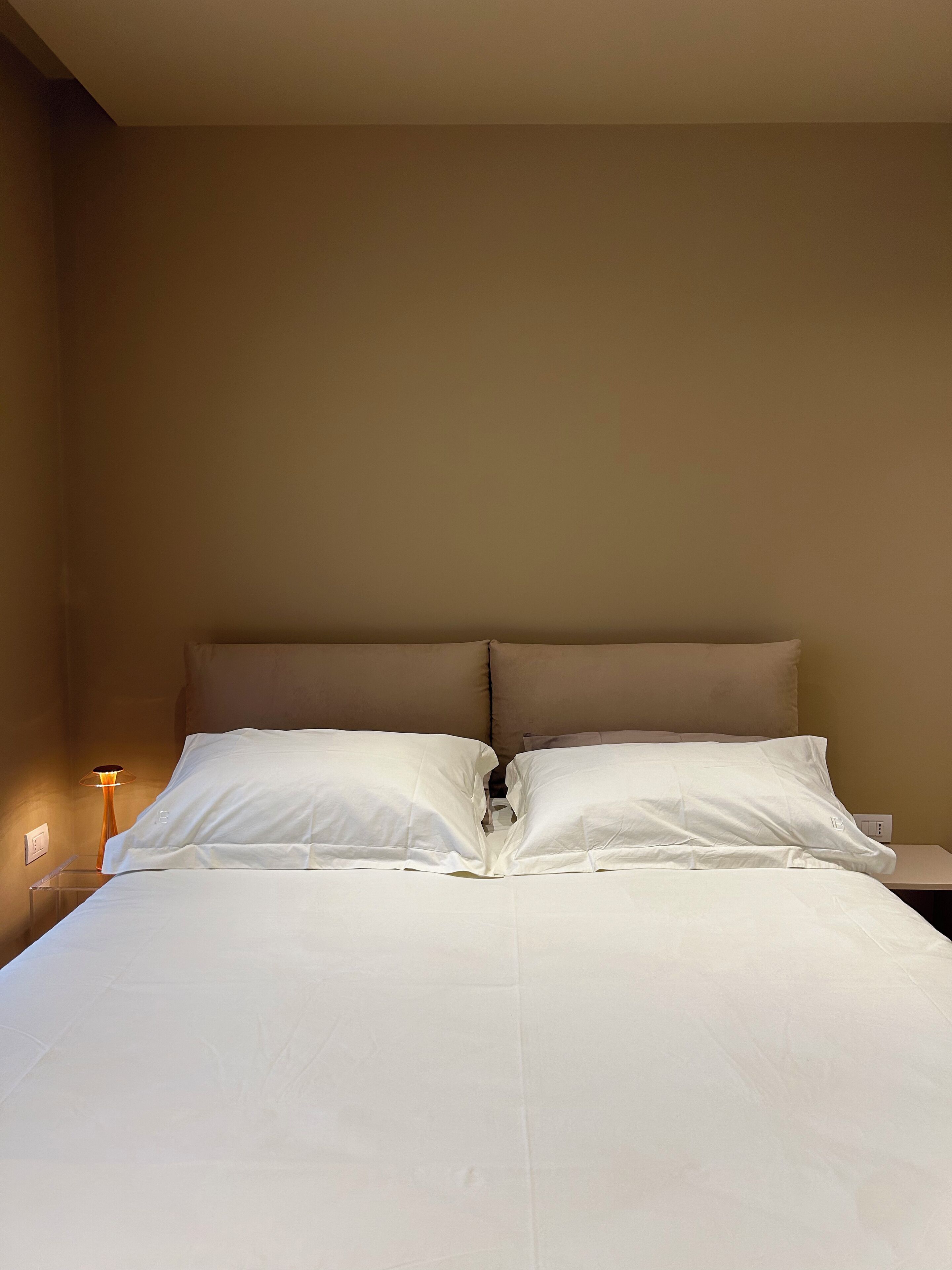 A neatly made bed with white linens in a hotel room.