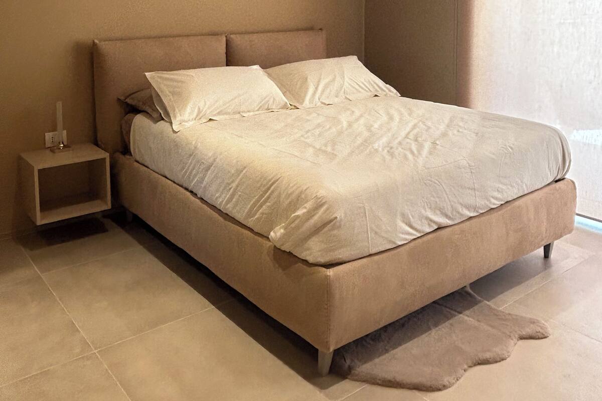 Une chambre à coucher avec un lit, une table de chevet et une fenêtre.