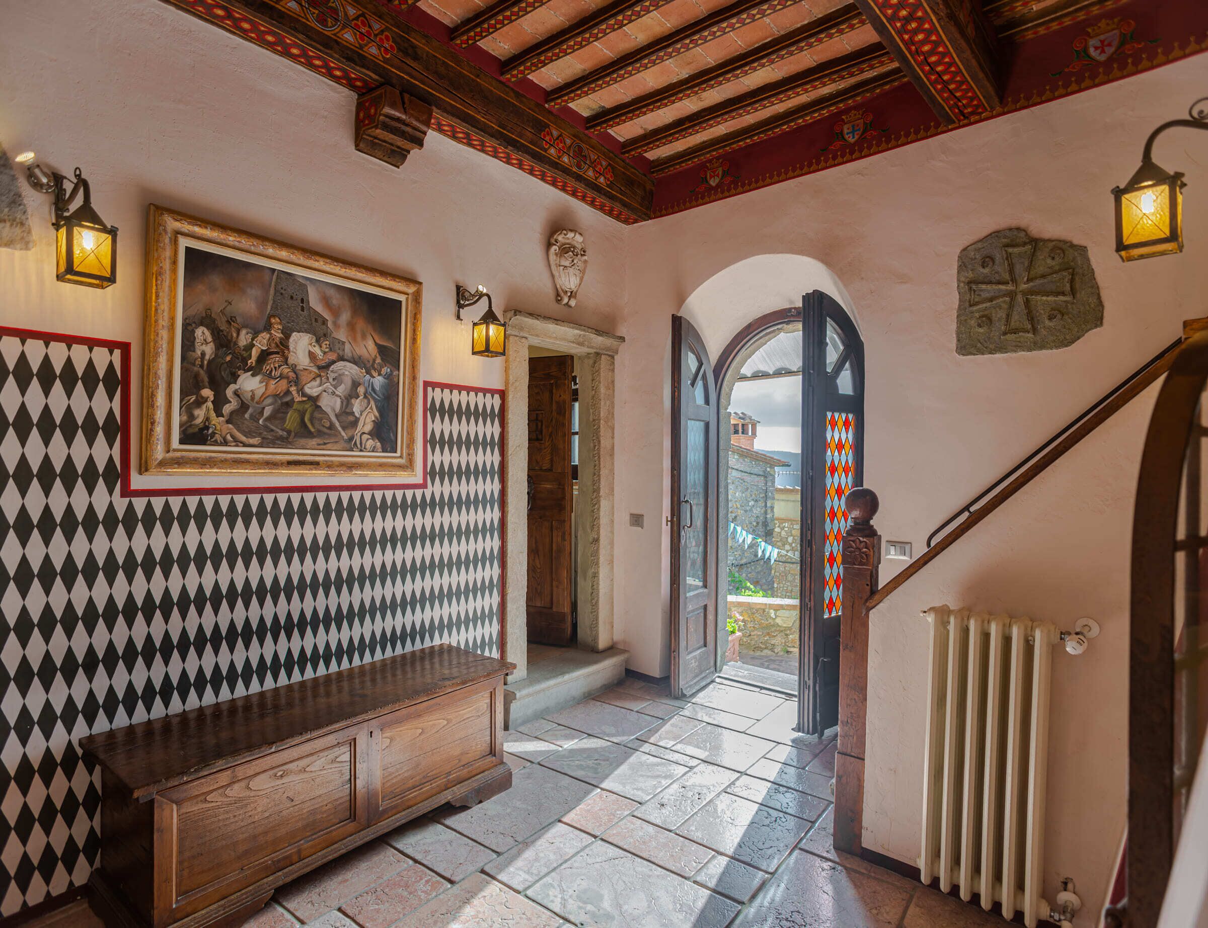 A hallway with a patterned wall, a wooden bench, a painting, and a staircase.