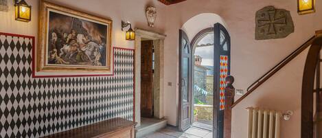A hallway with a patterned wall, a wooden bench, a painting, and a staircase.