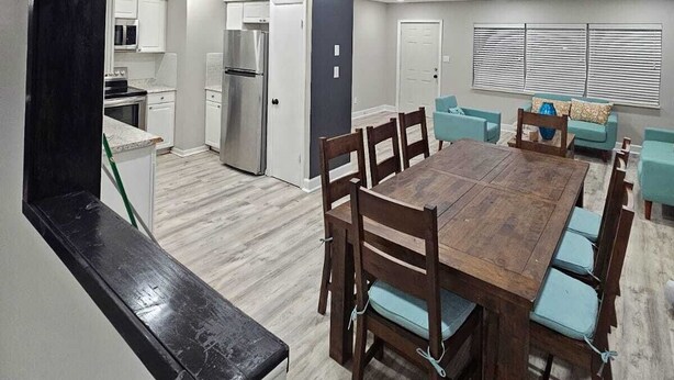 A modern kitchen with white cabinets, a stainless steel refrigerator, and a black countertop. - Renovated contemporary home centrally located (Gainesville)
