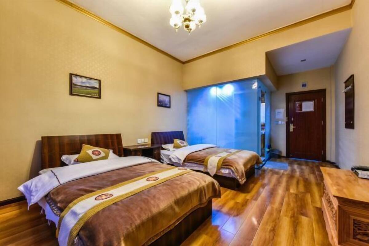 Une chambre d’hôtel avec deux lits, un plancher en bois, un lustre et une vue sur l’extérieur.