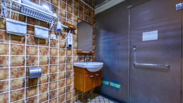 Une salle de bain avec un mur carrelé, un lavabo, un miroir et une porte.