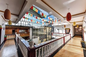 A hotel lobby with a glass staircase, wooden flooring, and a view of the city. - Lezhuang Linka Inn (Shangri-La)