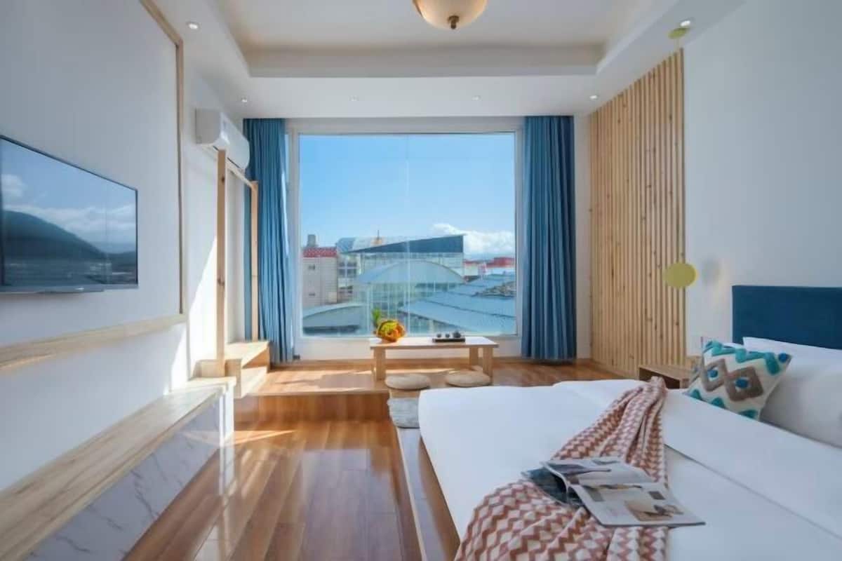 Une chambre d’hôtel moderne avec un grand lit, une vue sur la ville et un plancher en bois.
