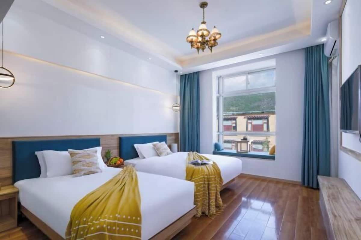 Une chambre d’hôtel avec deux lits, un lustre, une grande fenêtre donnant sur un beau paysage et un téléviseur à écran plat.