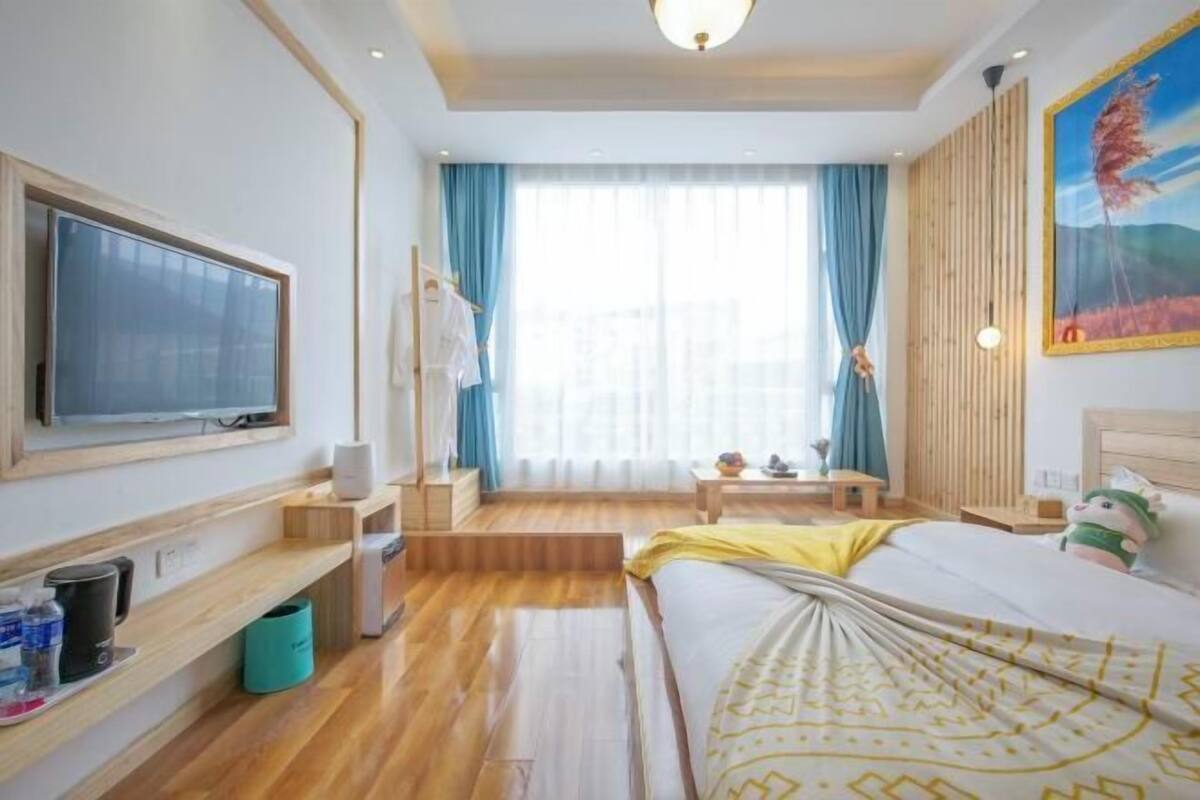 Une chambre d’hôtel avec un lit, une télévision, un bureau et une fenêtre avec des rideaux.