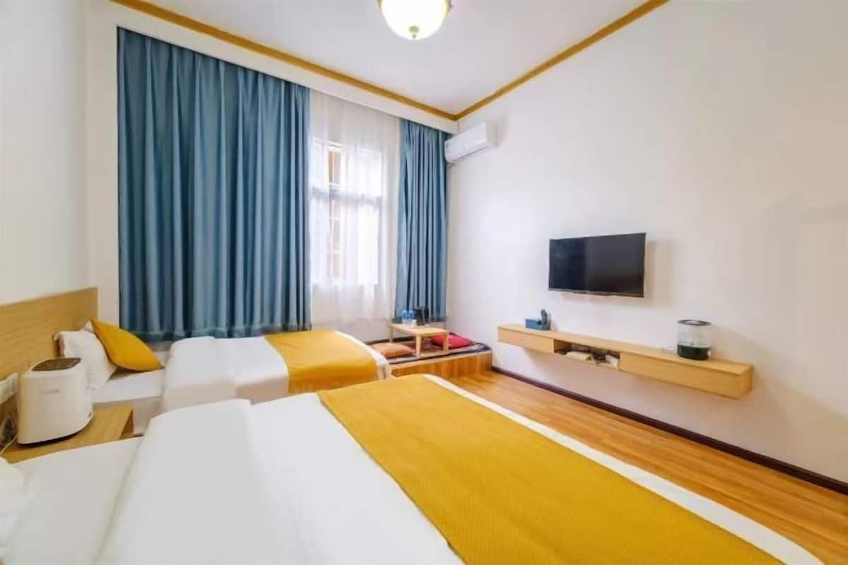 Une chambre d’hôtel avec deux lits, une télévision, une machine à café et une fenêtre avec des rideaux.