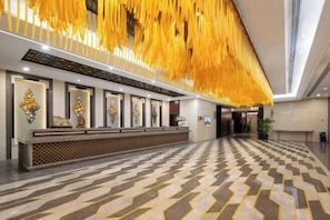 Un área de recepción con piso estampado, un mostrador de recepción y una pared decorada con cuadros.