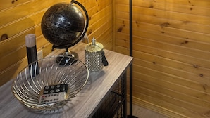 Un mur en bois orné d’une pancarte « Bienvenue », d’un globe terrestre et d’un panier en métal contenant des télécommandes.