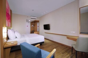 A hotel room with a bed, a desk, a chair, a TV, and a mirror. - Favehotel Nagoya - Batam (Nagoya)
