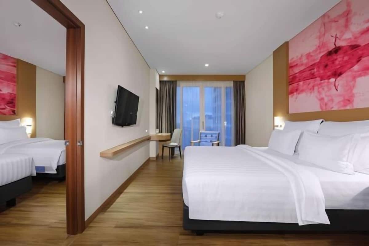 A hotel room with two beds, a TV, a desk, and a chair.