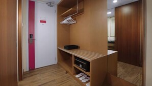 A hallway with a wooden floor, a white door with a red stripe, a wooden wardrobe, and a shoe rack. - Favehotel Nagoya - Batam (Nagoya)