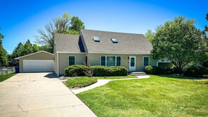Une maison de plain-pied avec un garage, une pelouse bien entretenue et un ciel dégagé.