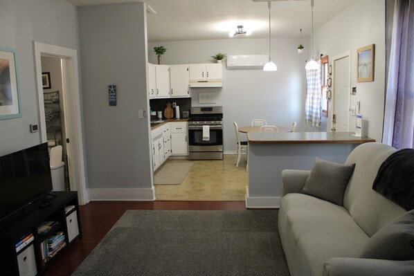 A modern kitchen with white cabinets, a built-in oven, and a dining area with a table and chairs.