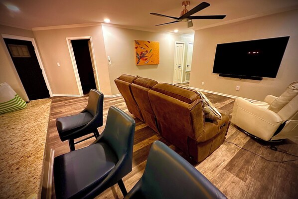 A living room with a TV, leather sofas, and a dining area with chairs. - Small elegante piece of art you can fall in love with & sleep in. (Victoria)