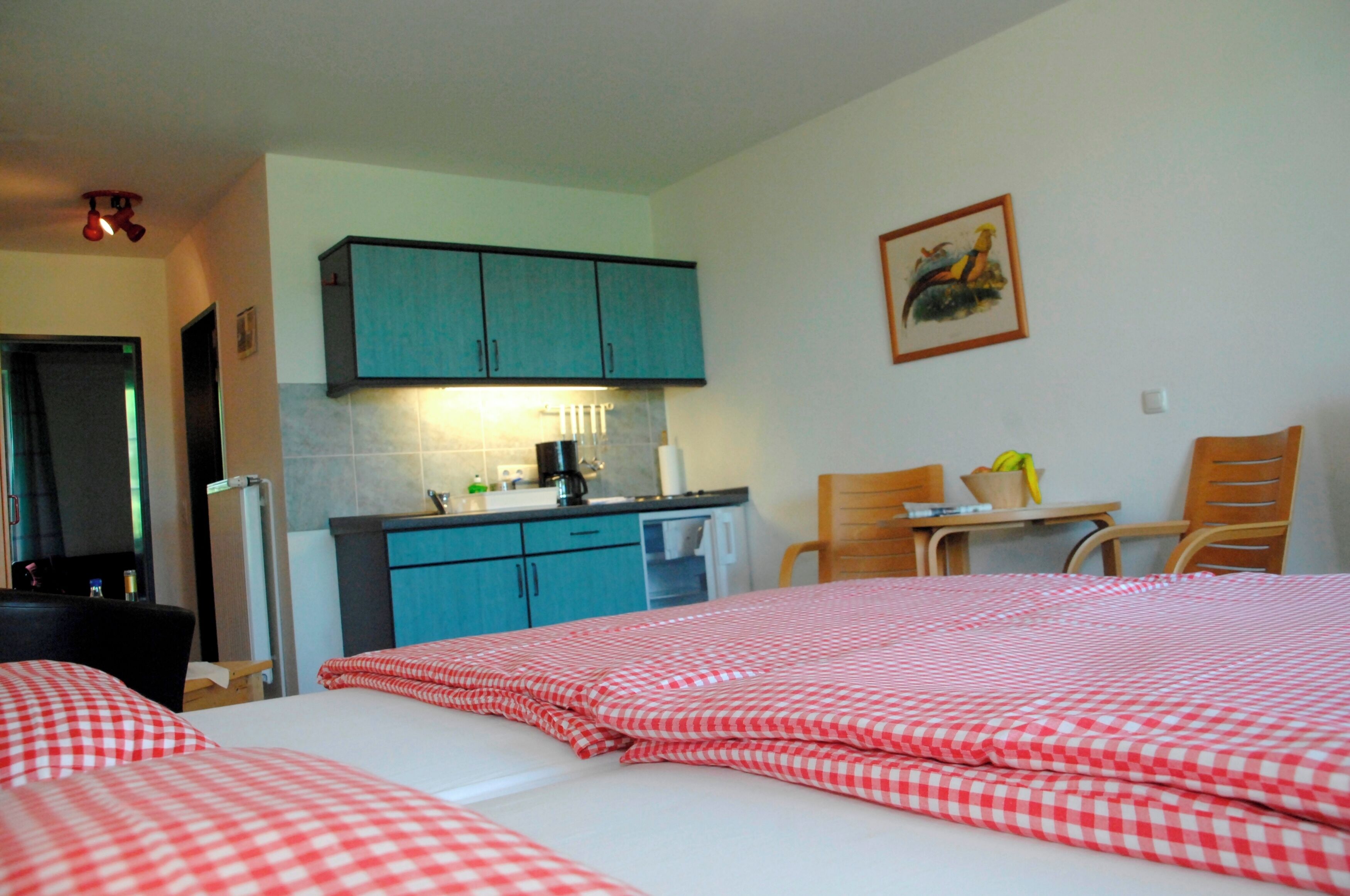 Une chambre d’hôtel comprenant un lit, un bureau, une chaise, une petite table et une kitchenette.