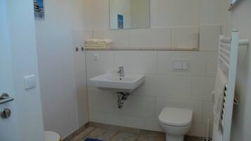 Une salle de bain avec un lavabo, des toilettes et un miroir au-dessus du lavabo.