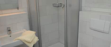A modern bathroom with a glass shower enclosure, a white sink, and a mirror.