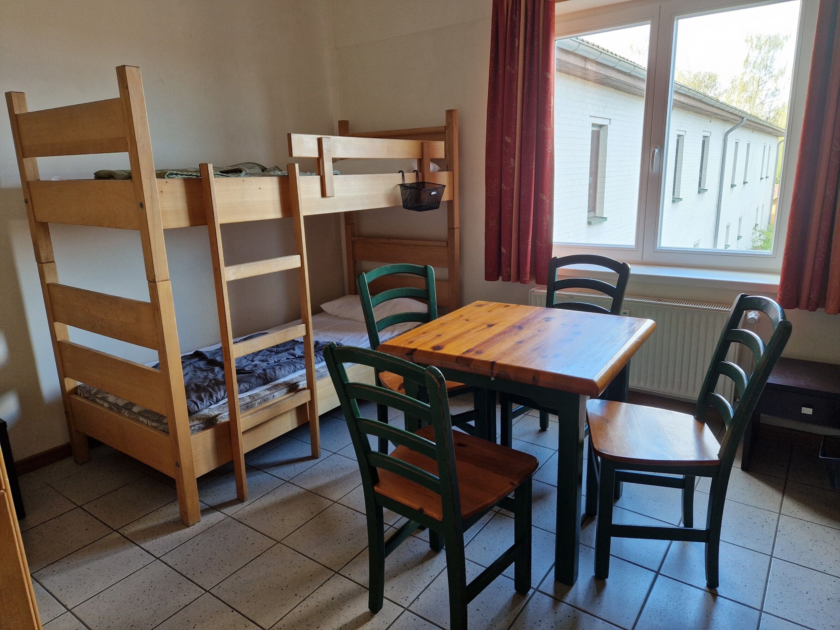 A room with bunk beds, a wooden table, and chairs.