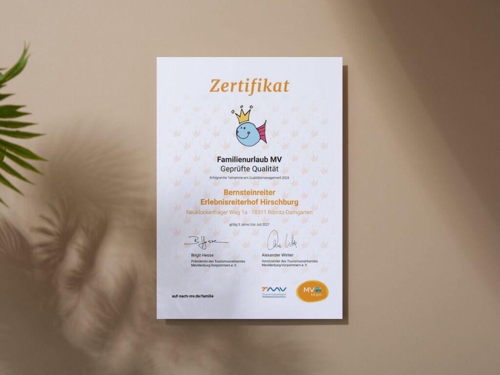 A certificate with text and signatures, placed on a surface with a plant in the background.