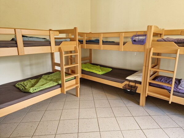 A bunk bed room with three levels, each with a wooden frame and mattress. - Bernsteinland Hirschburg (Ribnitz-Damgarten)