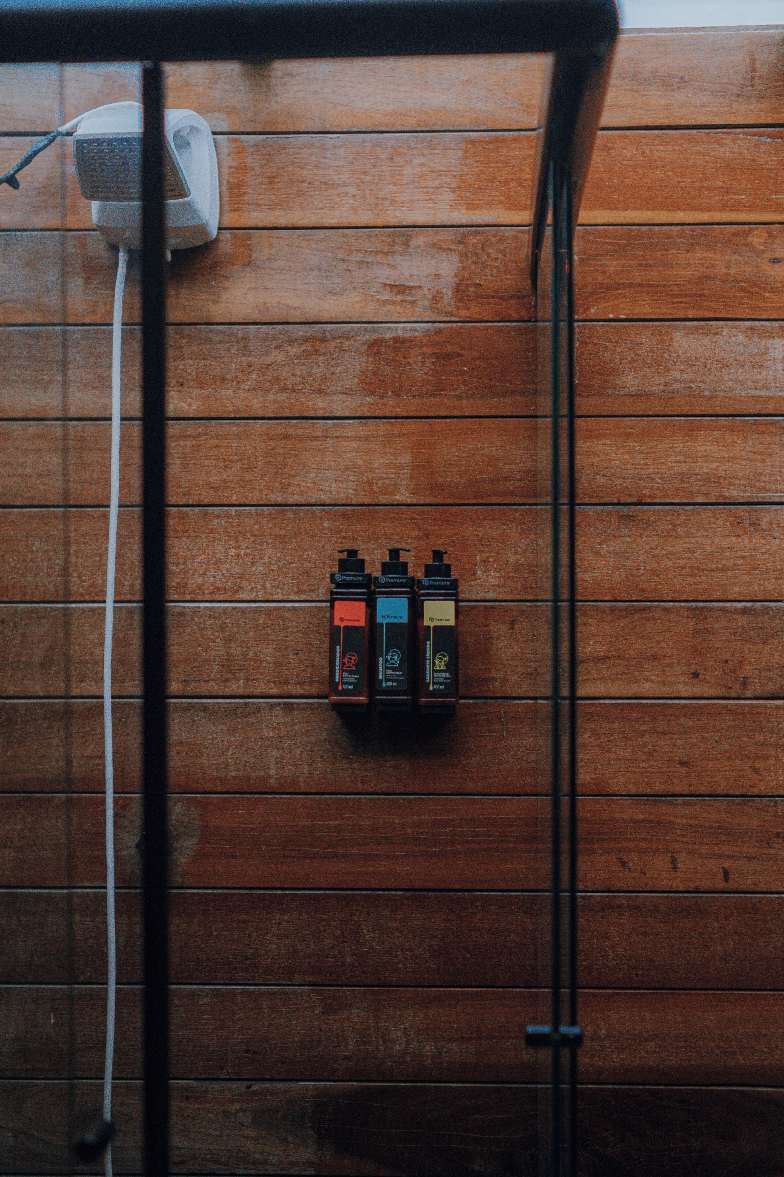 A wooden wall with three black dispensers labeled 'Premium' and a white electrical outlet with a cable.